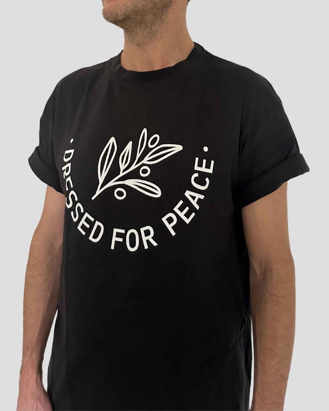 A man wearing off-lack shirt with a big dressed for peace logo