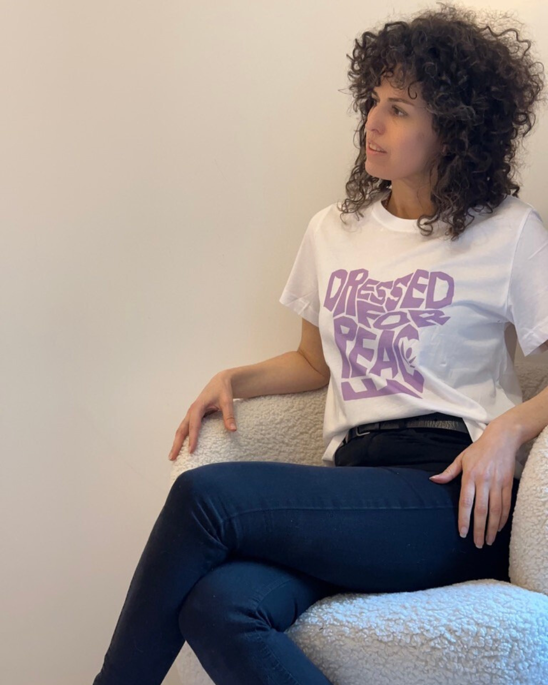 woman wearing white shirt with dressed for peace written in bold purple letters