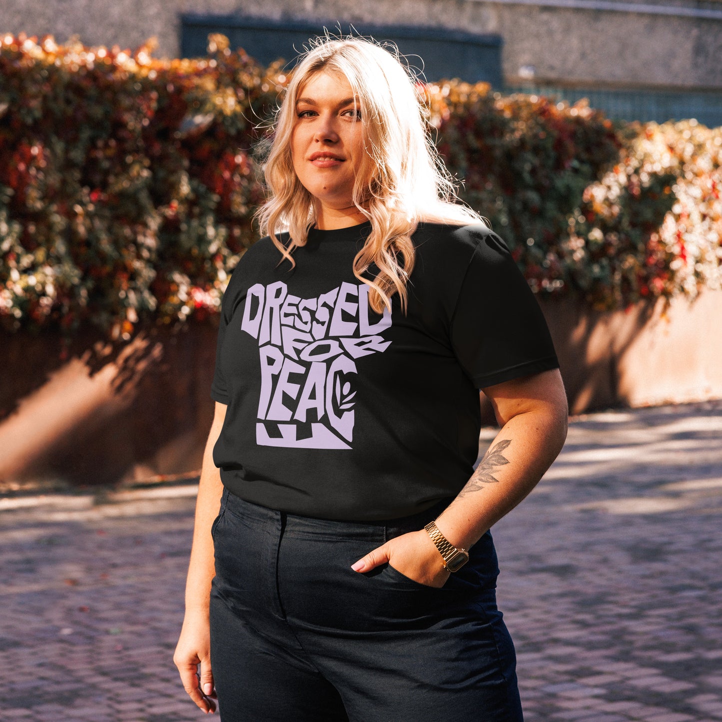 Person wearing a black t-shirt with white text standing outdoors.
