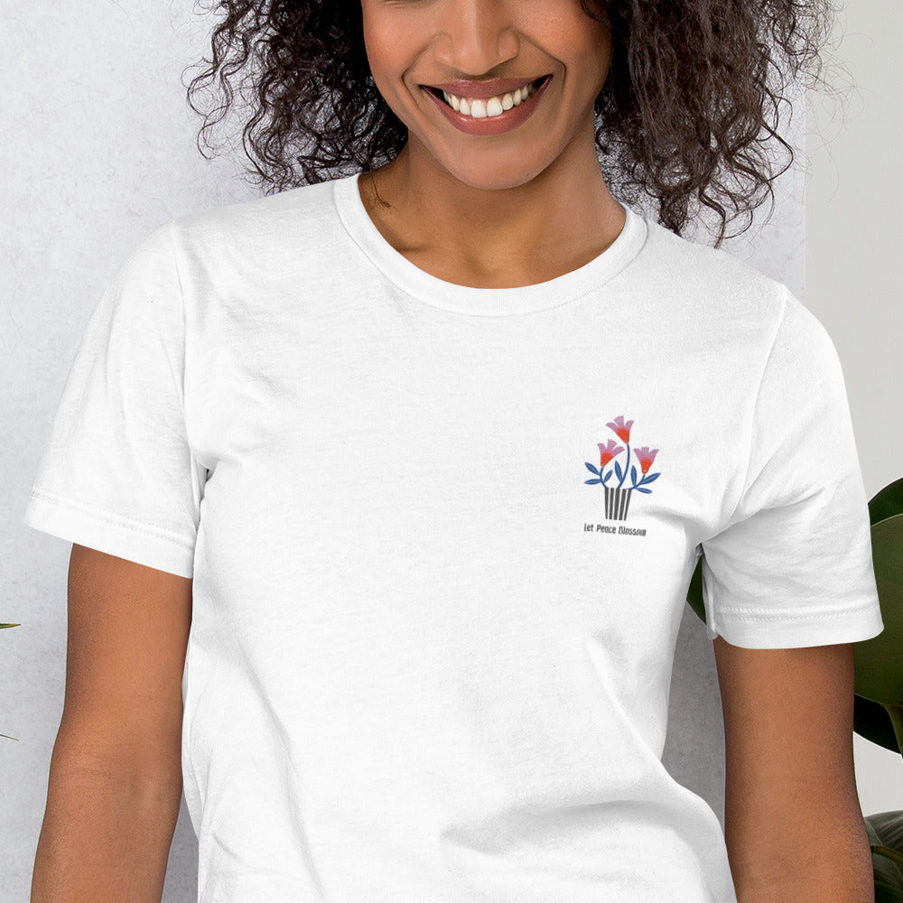 Person wearing a white t-shirt with a colorful logo on a light gray background