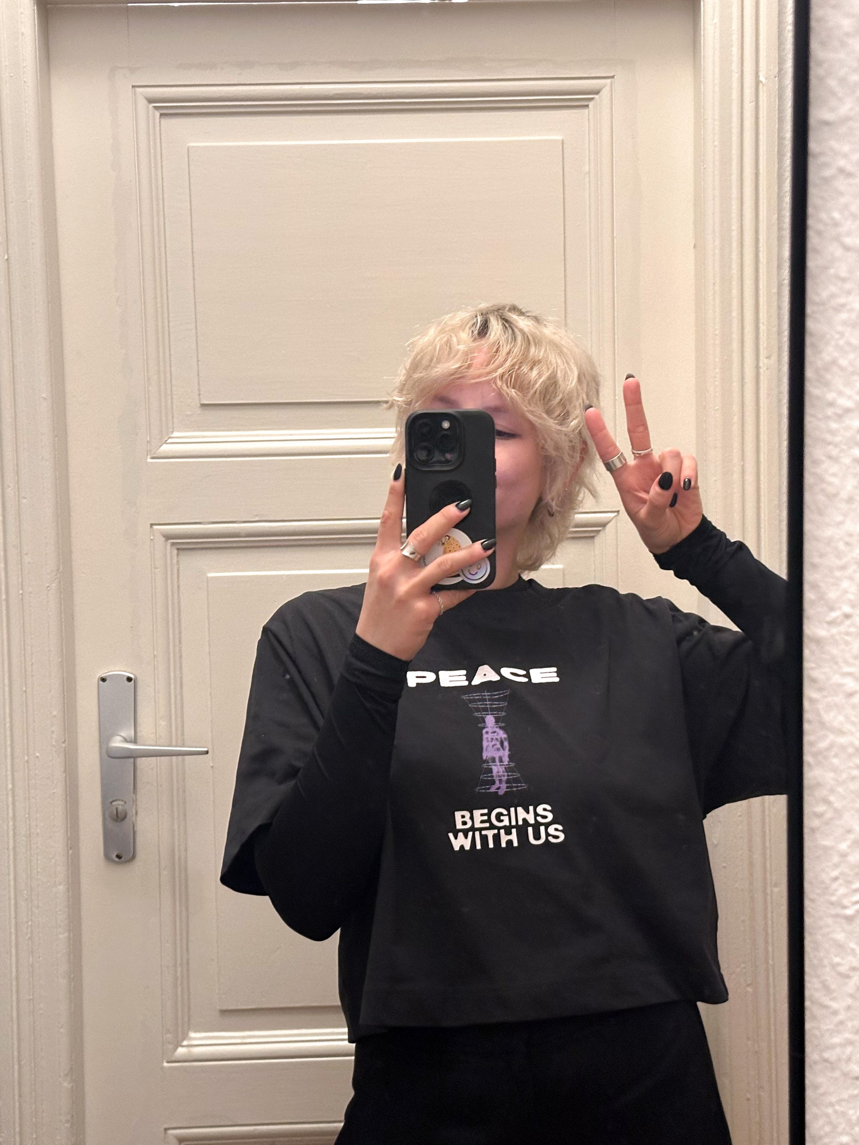 a woman wearing peace begins with us T